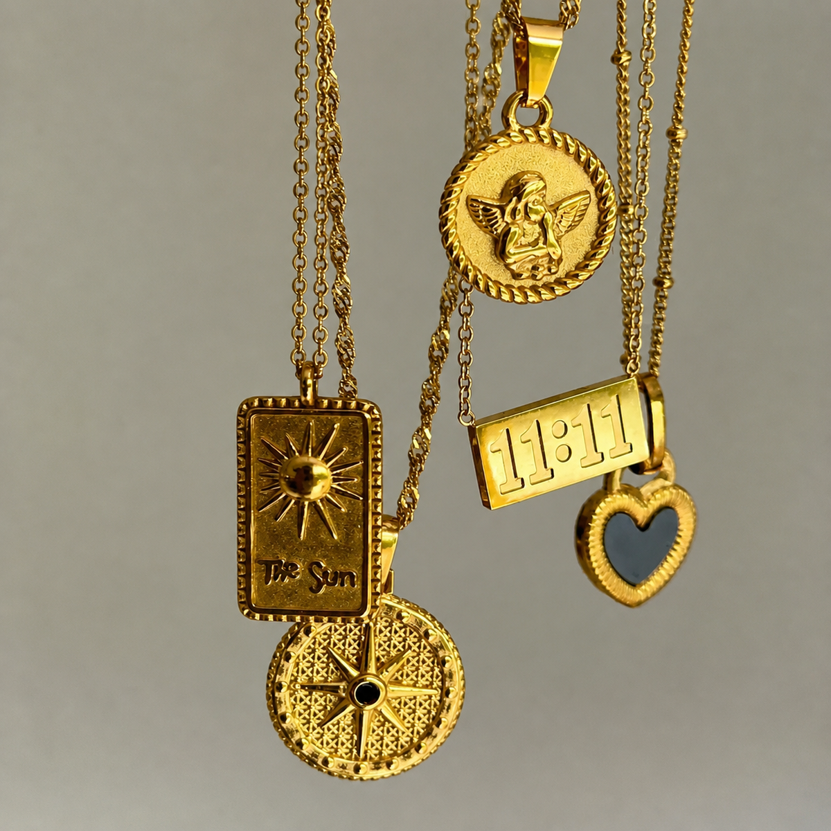 Several gold pendant necklaces hanging together, with the round cherub medallion at the top beside a sun tag, a star disc and a heart. 5