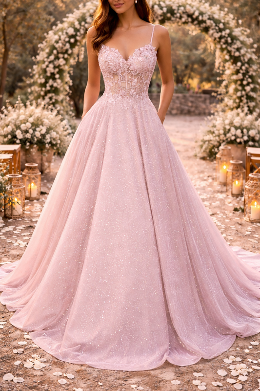 Front view of a woman in a pale pink sparkly tulle ball gown with lace bodice, standing under a flower arch. 1