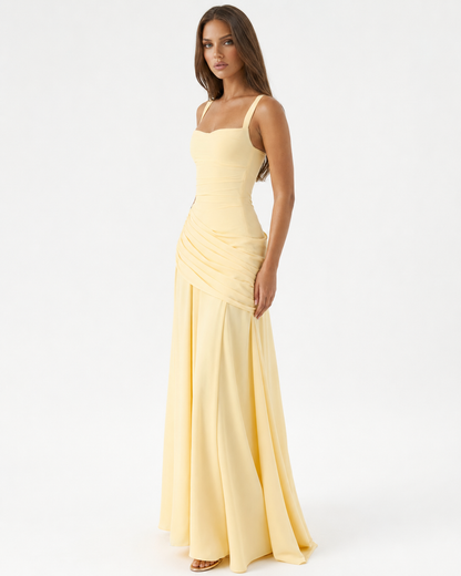 Pale yellow dress worn by a model, three-quarter view showing the square neckline, wide straps and draped hip. 2