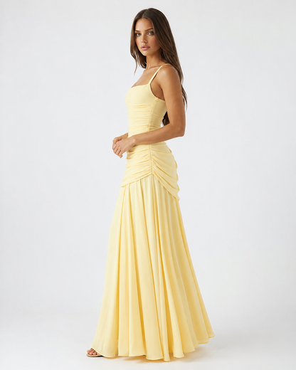 Side view of the pale yellow maxi dress, showing ruched side gathering at the hip and the flowing skirt. 3
