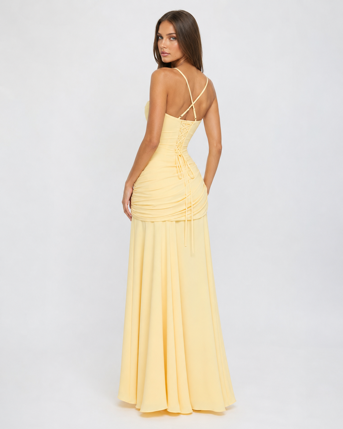 Back view of the pale yellow dress with crossed straps, lace-up corset back and ruched hip detail. 5
