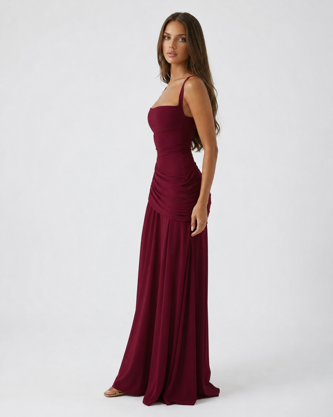 Side view of the burgundy dress with thin straps, ruched hip and long flowing skirt. 10
