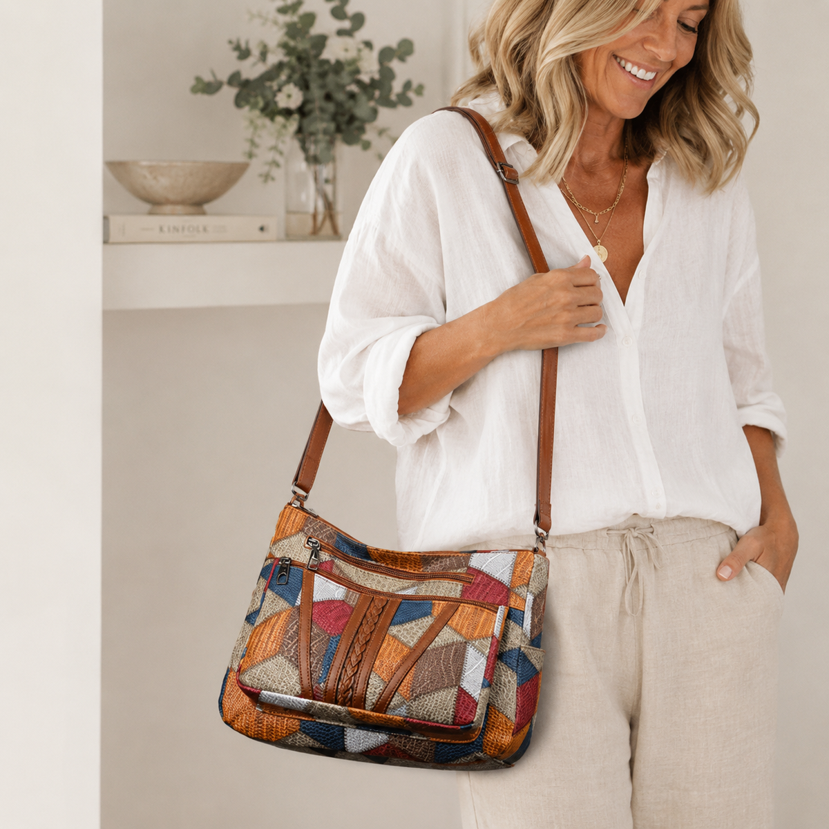 Smiling woman in a white linen shirt and cream trousers carrying the patchwork bag on her shoulder. 2