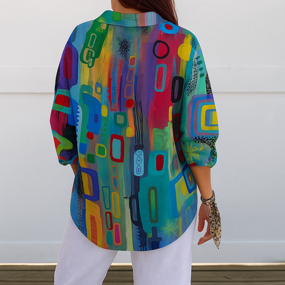 Back view of a model wearing the blouse, showing the continuous multicoloured abstract print across the back and sleeves, with a curved hem. 7