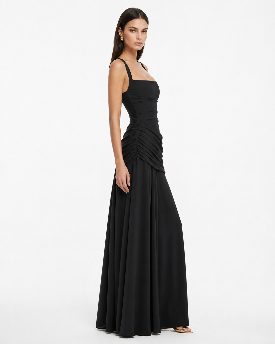 Black dress on a model in side view, showing the square neckline, ruched hip and long skirt. 12