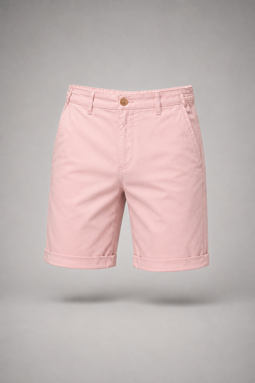 Pink cuffed shorts with an elasticated side waistband and wooden-look button, shown flat against a plain grey studio backdrop. 1