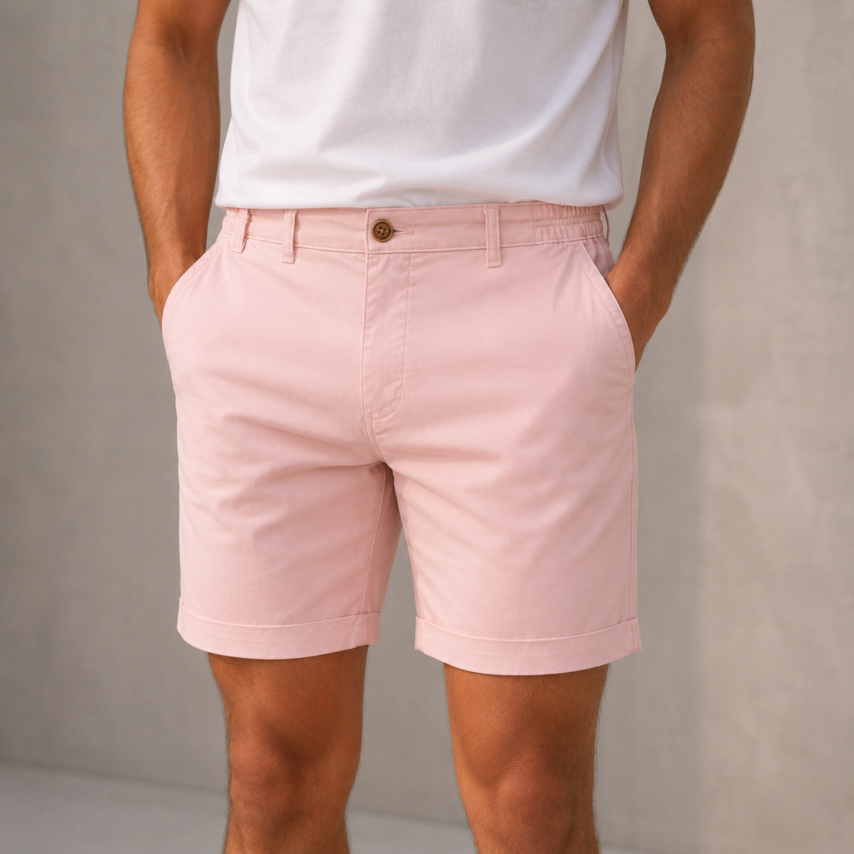 Close-up of a model wearing pink cuffed shorts with a white t-shirt, hands in the side pockets. 4