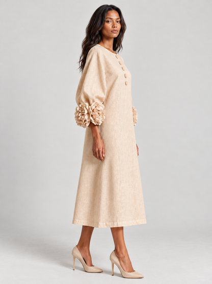 Side view of the beige dress on a model turned to the camera, showing the sleeve volume, floral cuff and A-line skirt. 3