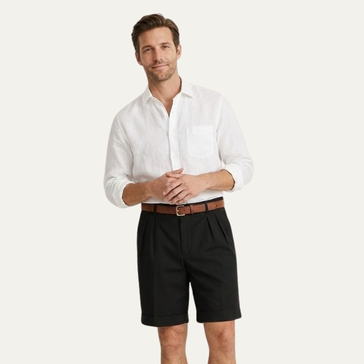 Man with clasped hands wearing black pleated turn-up shorts, a tan belt and a white linen shirt. 10