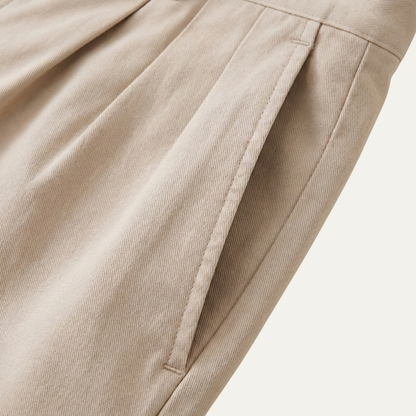 Close-up of the stone twill fabric, showing a stitched side pocket opening and the fold of a pleat. 4