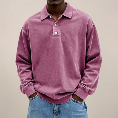 Front view of the relaxed polo in washed dusty pink, worn by a model with hands in jeans pockets. 10