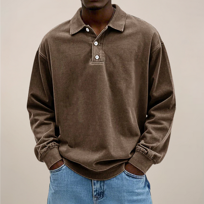 Model wearing the washed polo in chocolate brown, front view, hands in jeans pockets, ribbed cuffs and hem visible. 3