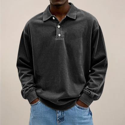 Front view of the polo in washed charcoal black, worn with light blue jeans, showing the relaxed fit and ribbed hem. 8