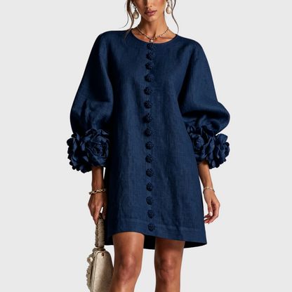 Front view of the dress in navy blue on a model, with matching flower buttons and rosette sleeve trims. 3