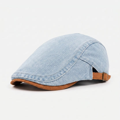 Light blue denim flat cap shown from the front left against a plain white background, with tan peak and rear buckle strap. 3