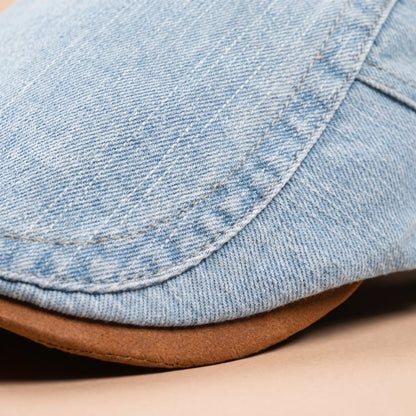 Close-up of the light blue denim texture, contrast stitching and the tan suede-look underside of the peak. 4