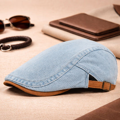 Light blue denim flat cap styled on a beige surface with sunglasses, a braided bracelet and brown leather wallets. 5