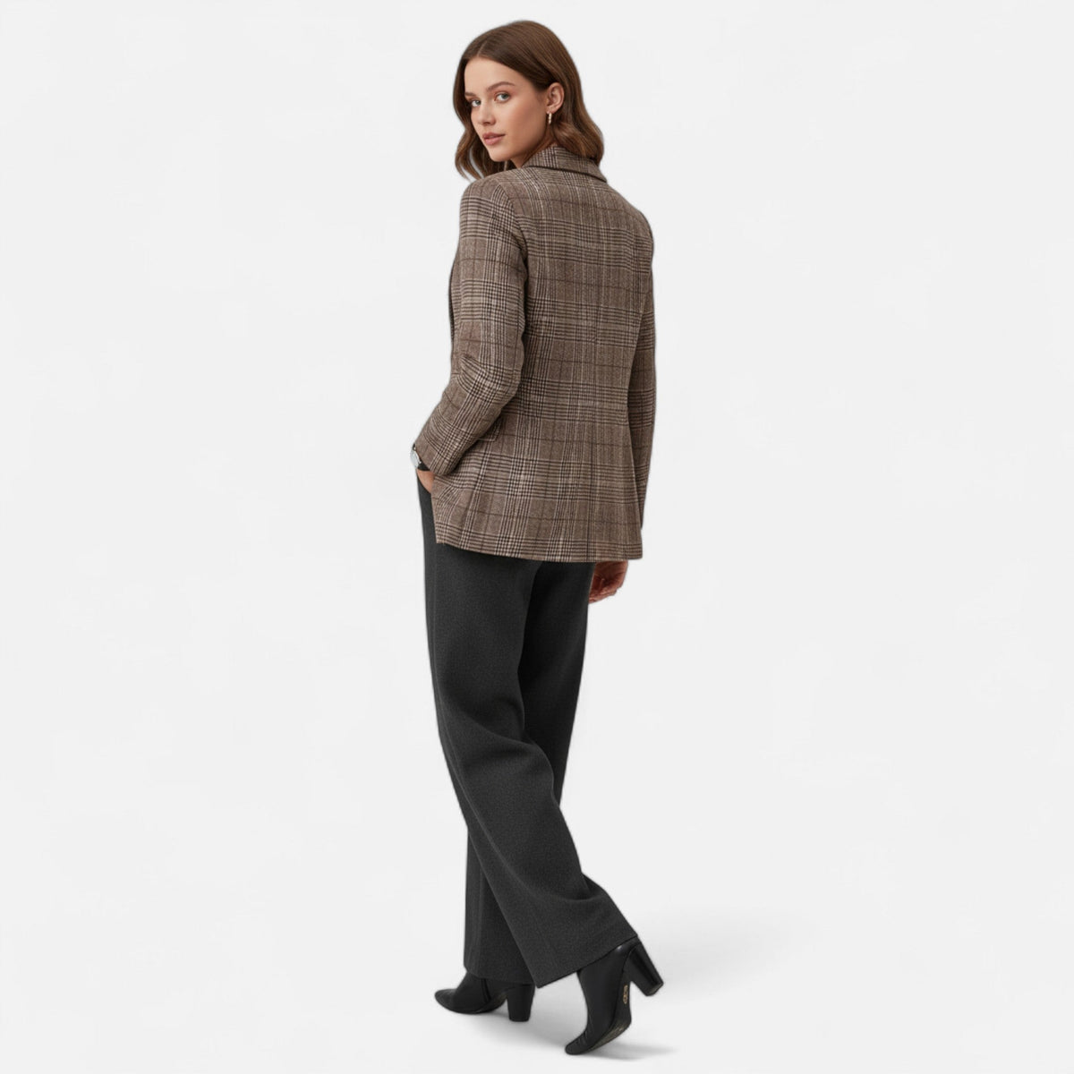 Back view of a model glancing over her shoulder in the brown checked blazer, with grey trousers and black heeled ankle boots. 3