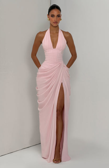 Pale pink halterneck gown worn by a model posed against a plain two-tone wall, with the thigh-high slit on show. 8