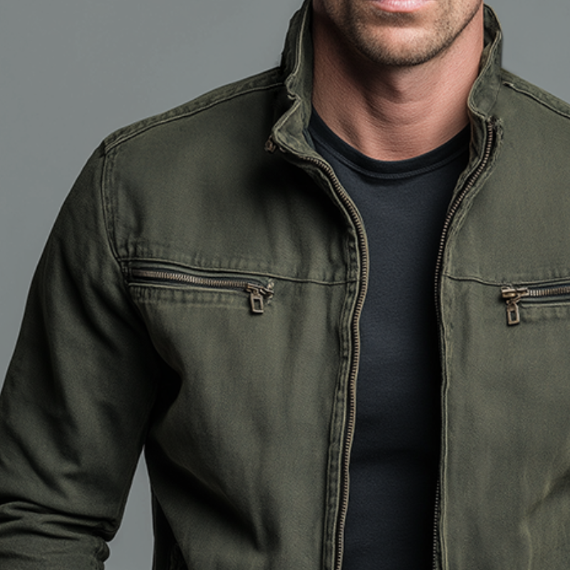 Close-up of the olive green jacket's stand collar, front zip and two zipped chest pockets with brass-coloured pullers. 2