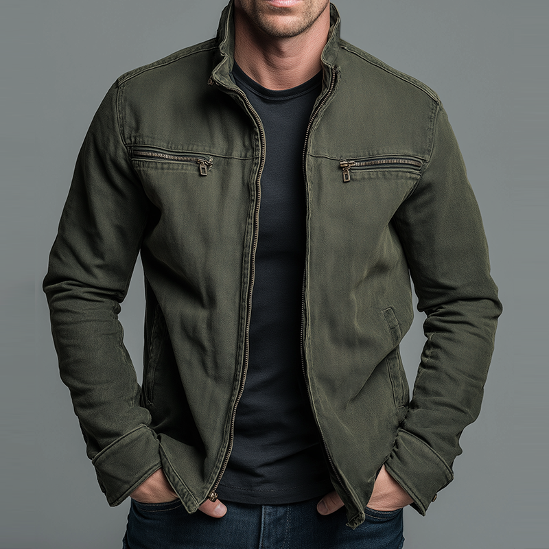 Man wearing an olive green zip-up jacket with chest zip pockets over a black T-shirt, hands in pockets, front view. 1