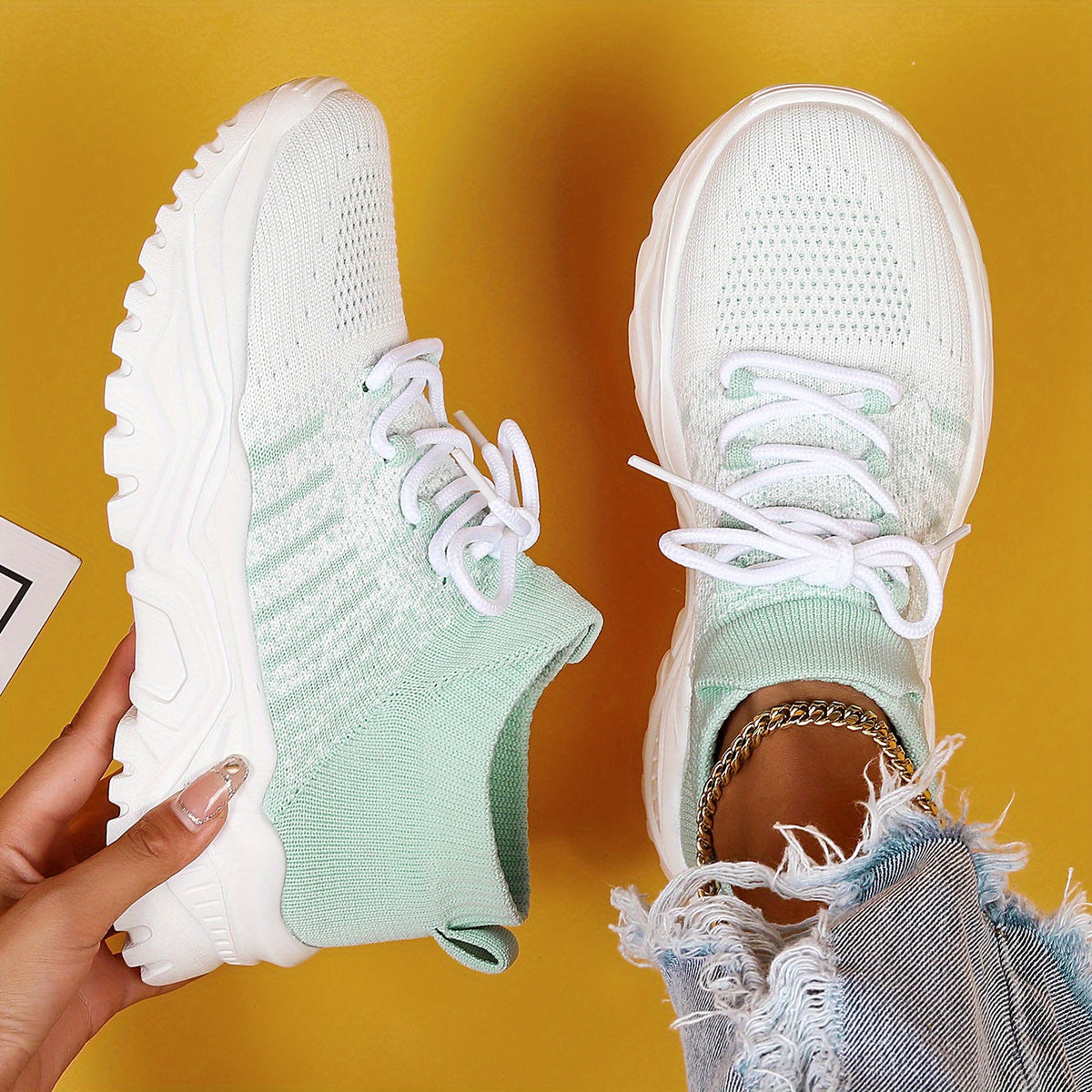Top-down view of white and pale green gradient knit sneakers with white laces and chunky white soles on a yellow background. 16