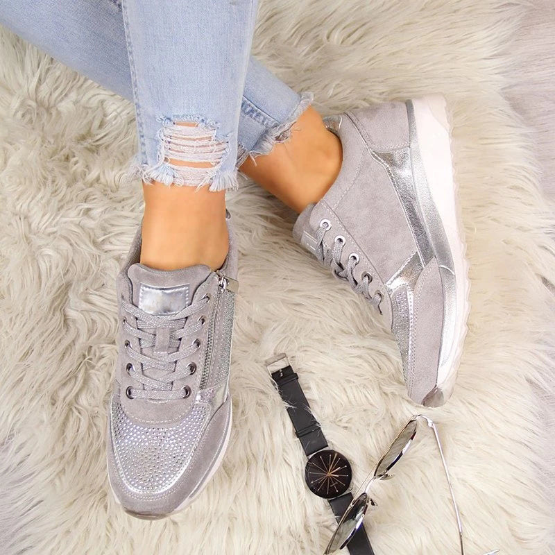 Overhead view of the grey trainers worn on a fluffy cream rug, with a wristwatch and sunglasses beside them. 6