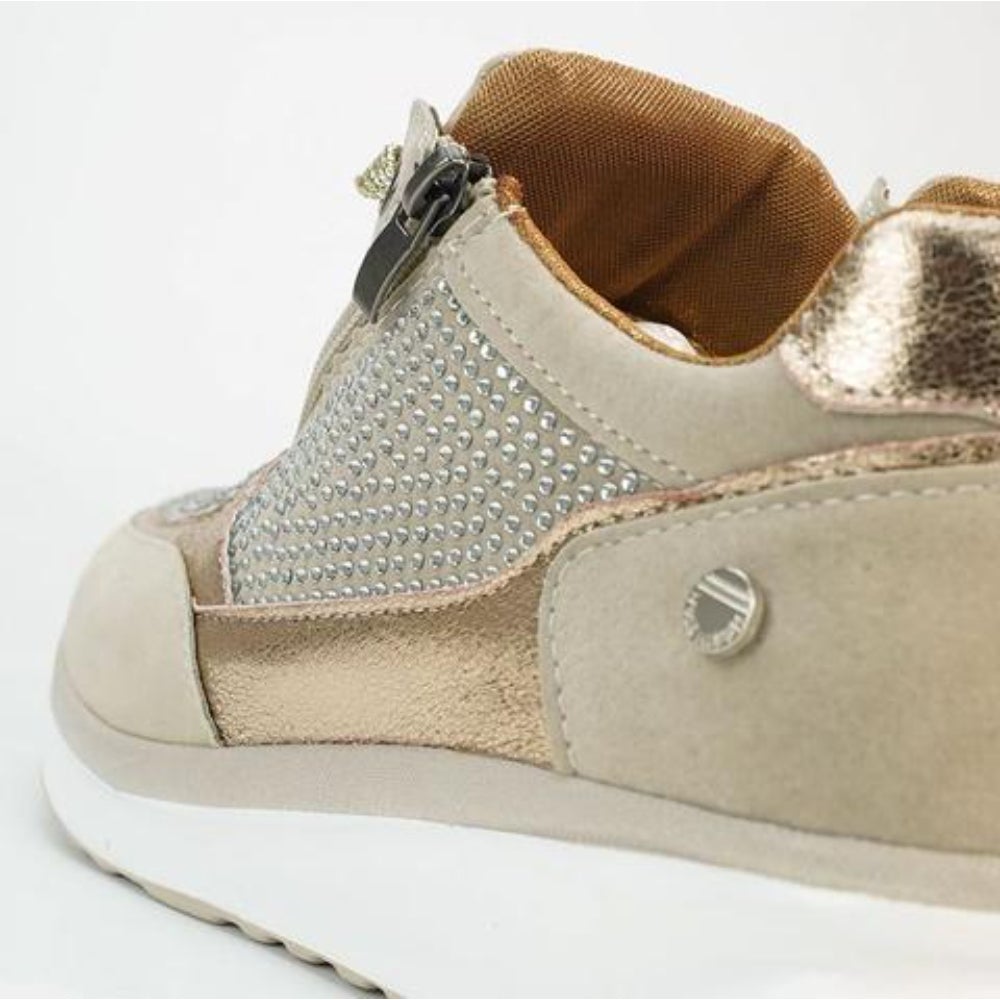 Close-up of the heel and side of the beige trainer, showing the zip pull, rhinestone panel, metallic trim and tan lining. 9