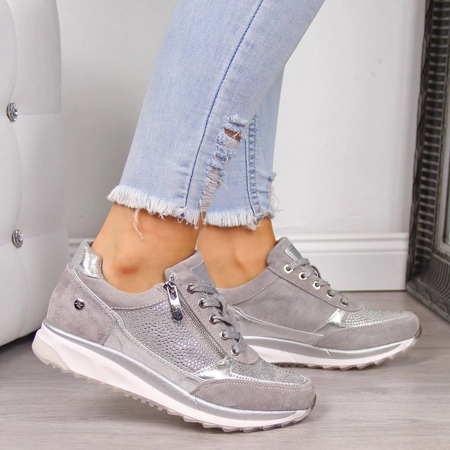 Model wearing the grey version of the lace-up trainers, showing the side zip, silver trim and sparkly studded panel. 2