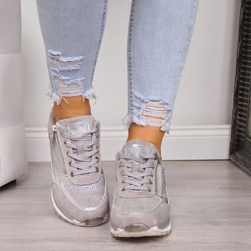 Front view of the grey trainers worn by a model, showing the lacing, silver tongue patch and zips on the outer sides. 5
