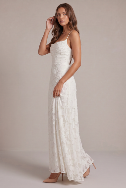 Side view of the white maxi dress on a model with one hand raised to her hair, showing the fitted shape and flowing skirt. 12