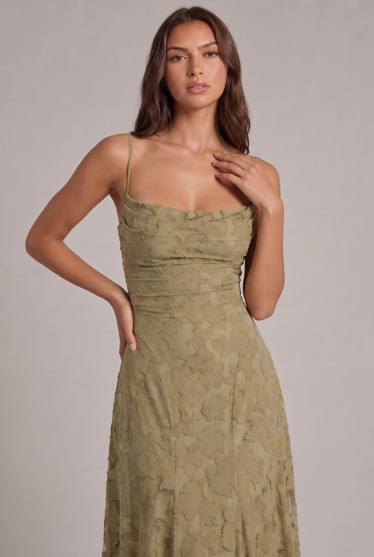 Close-up of the olive green dress bodice on a model, showing the cowl neckline and layered floral texture. 14