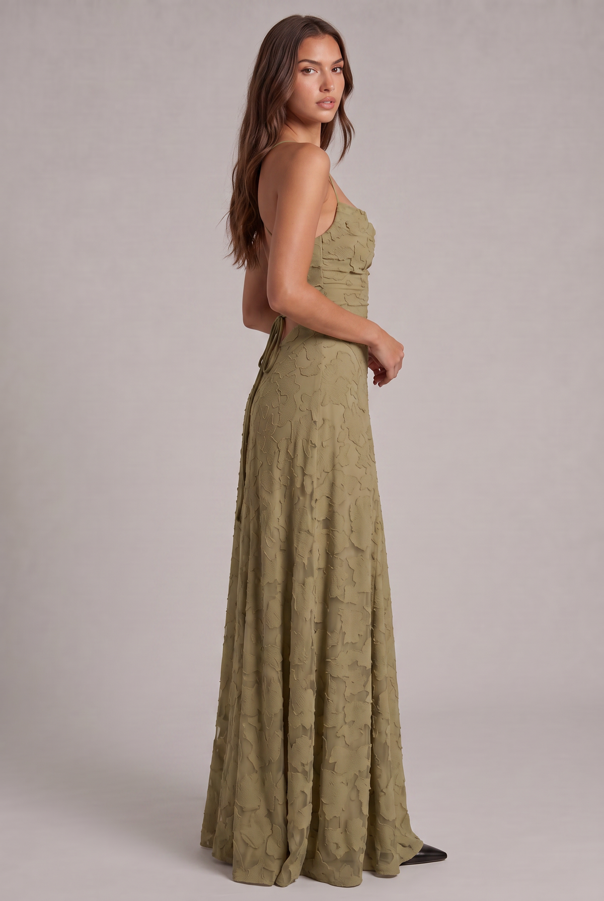 Side-back view of the olive green maxi dress on a model looking over her shoulder, showing the low back and tie. 16