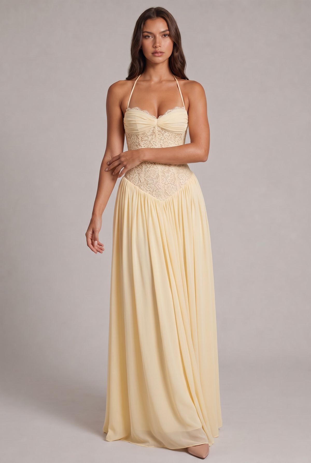 Model facing the camera in the pale yellow maxi dress, with lace corset bodice, halter straps and full chiffon skirt. 5