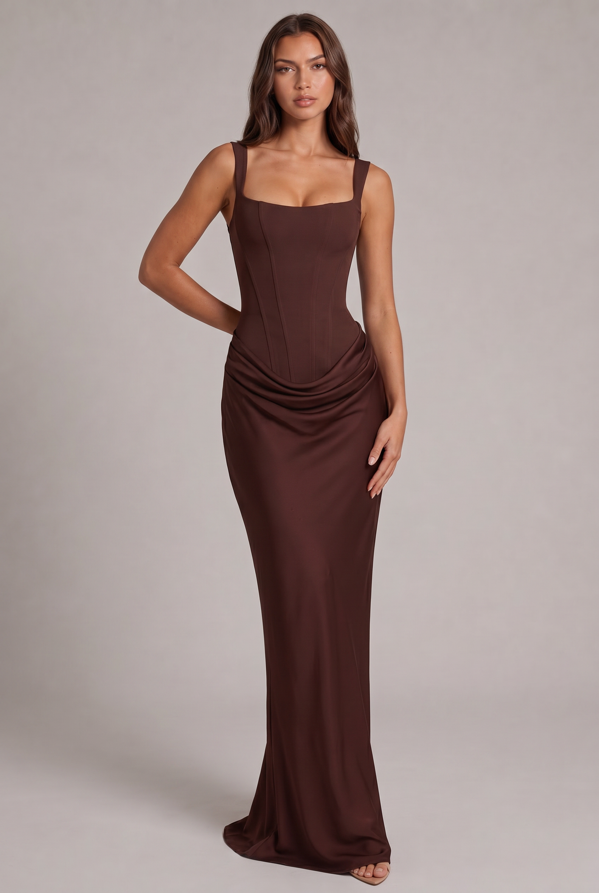 Model wearing the chocolate brown maxi dress, front view, showing the structured corset bodice, square neckline and draped skirt. 1