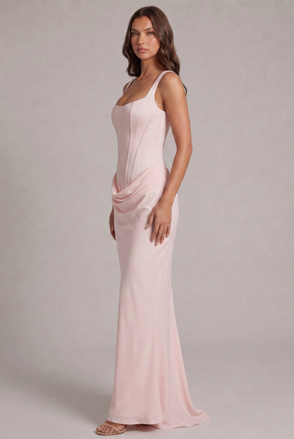Side view of the pale pink maxi dress, showing the fitted corset bodice, draped hip detail and flowing skirt with a small train. 27