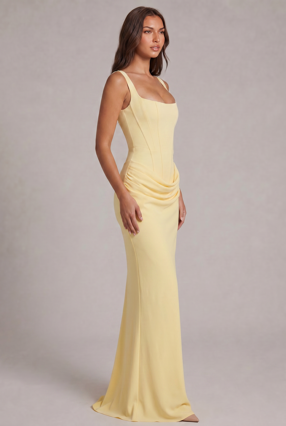 Three-quarter side view of the pale yellow maxi dress, showing the fitted corset bodice, hip drape and floor-skimming skirt. 23