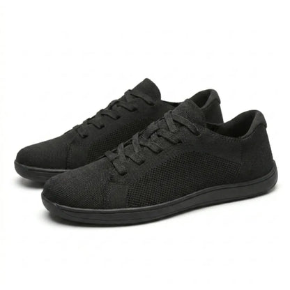 Pair of black knit lace-up trainers at an angle, showing the mesh side panels and the thin flat sole. 16