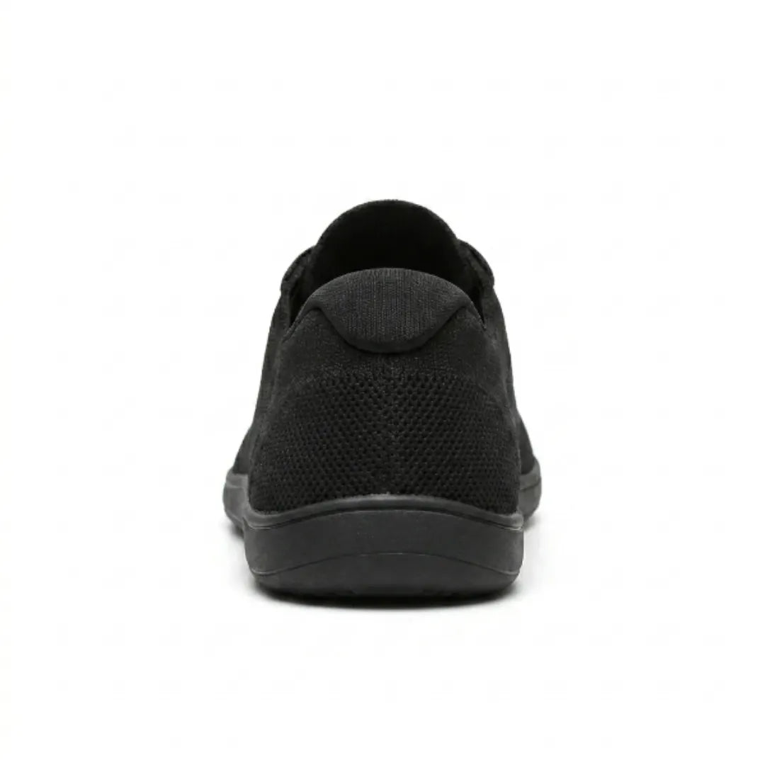 Rear view of a black knit trainer showing the padded heel collar, mesh heel panel and flat sole. 18