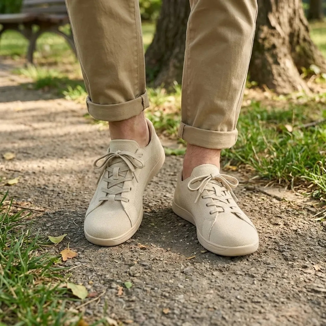 Pair of beige knit trainers worn with rolled khaki trousers, standing on a park path beside grass. 2