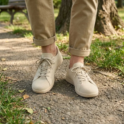 Pair of beige knit trainers worn with rolled khaki trousers, standing on a park path beside grass. 2