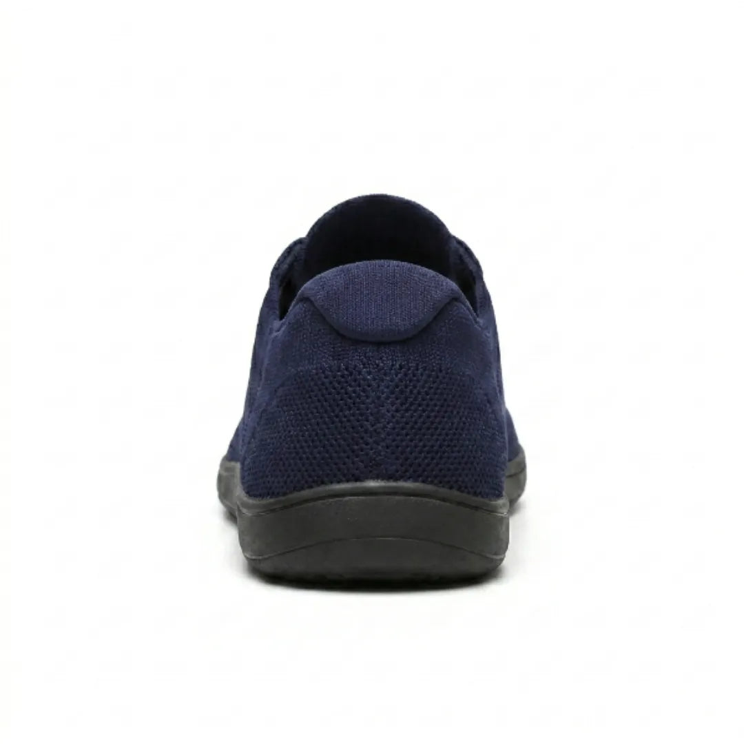 Navy knit trainer seen from behind, showing the padded heel tab, textured mesh and flat black sole. 27