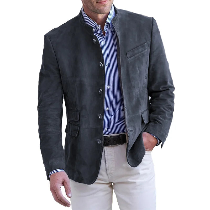 Man wearing the stand-collar button-front jacket in charcoal over a blue striped shirt and cream trousers, hand in pocket. 4