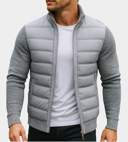 Man wearing the quilted jacket in light grey with knitted sleeves and ribbed hem, worn open over a white t-shirt. 2