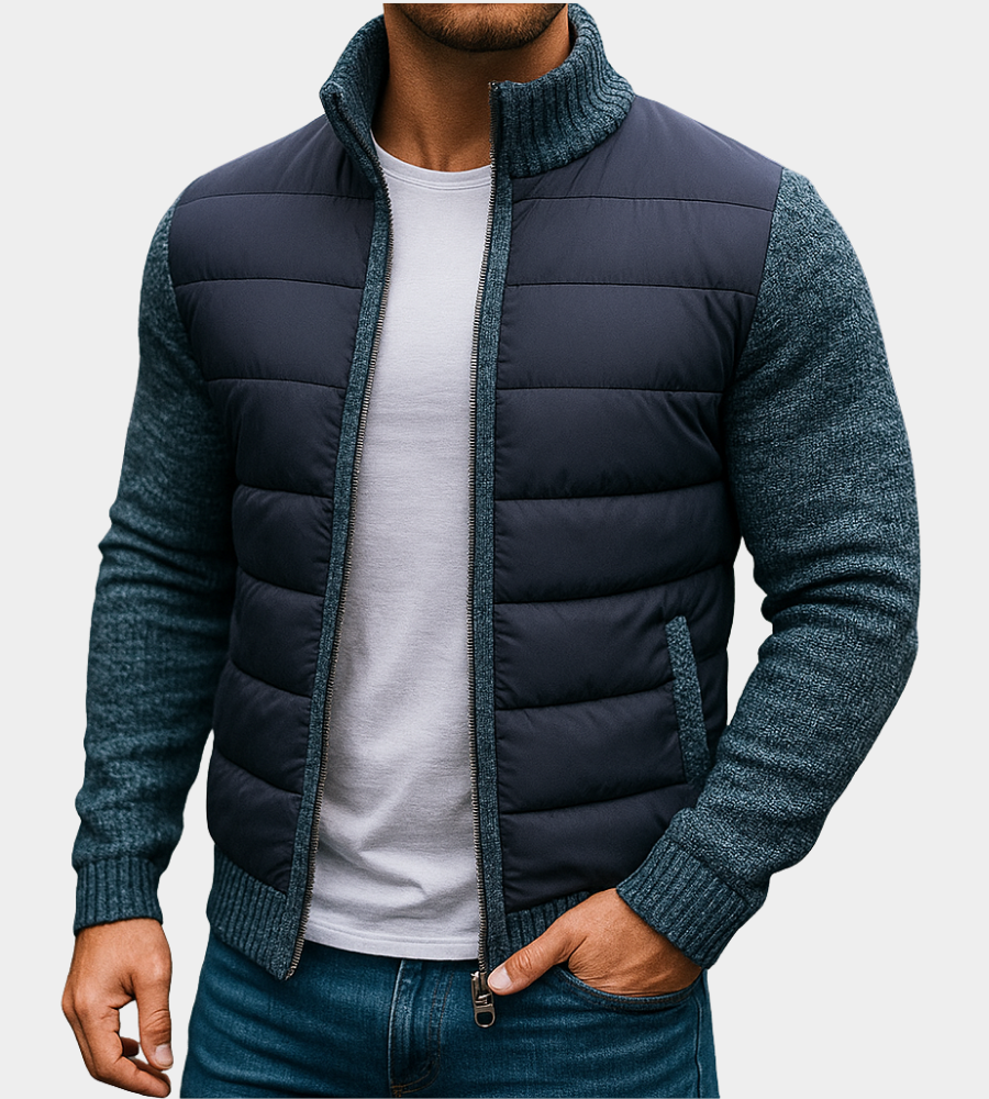 Man wearing the quilted jacket in navy with blue-grey knitted sleeves and collar, one hand in his jeans pocket. 4