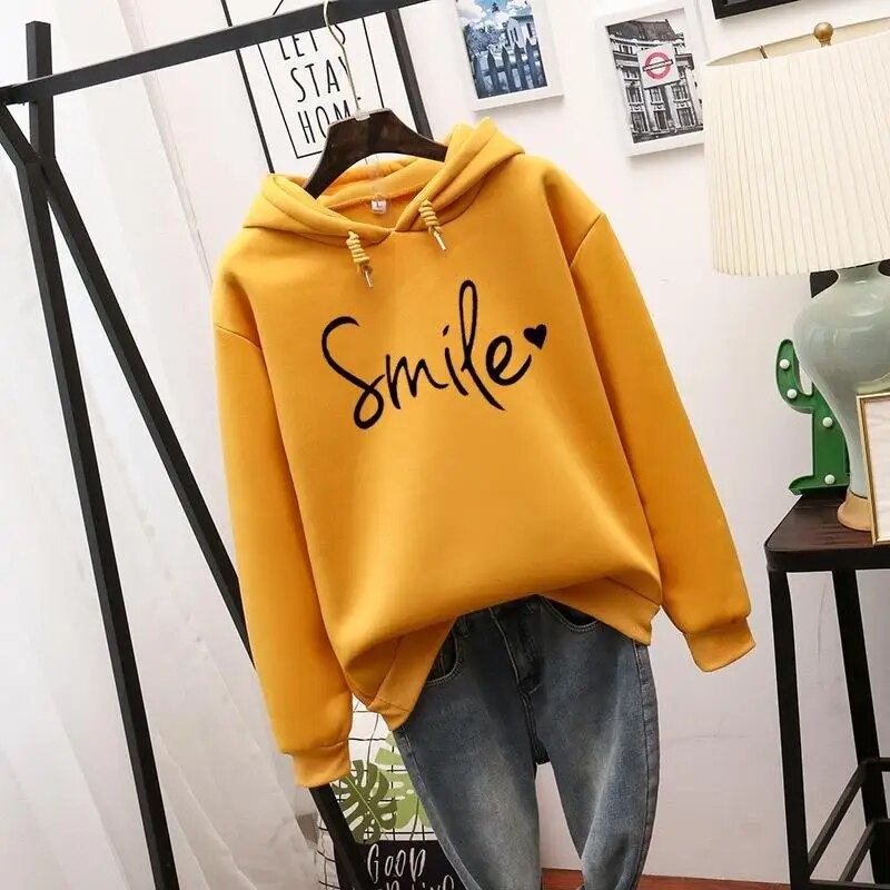 Mustard-yellow hooded sweatshirt with black script slogan and heart on the chest, ribbed cuffs and drawstrings, shown with blue jeans. 4