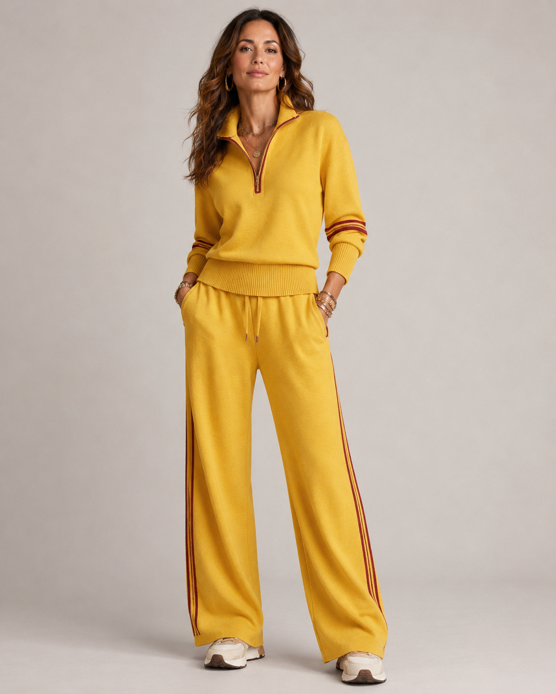 Model standing with hands in pockets in the mustard yellow set, with deep red stripes on sleeves and trouser sides. 3