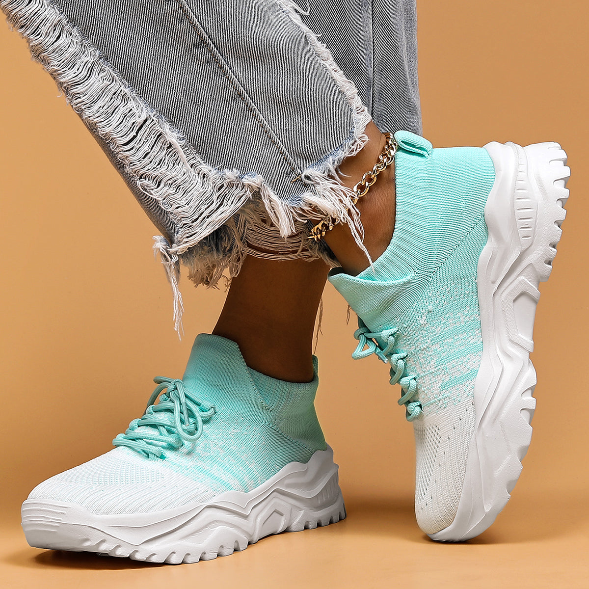Mint green and white gradient knit sneakers with chunky white soles, worn with frayed grey jeans and a gold anklet. 10
