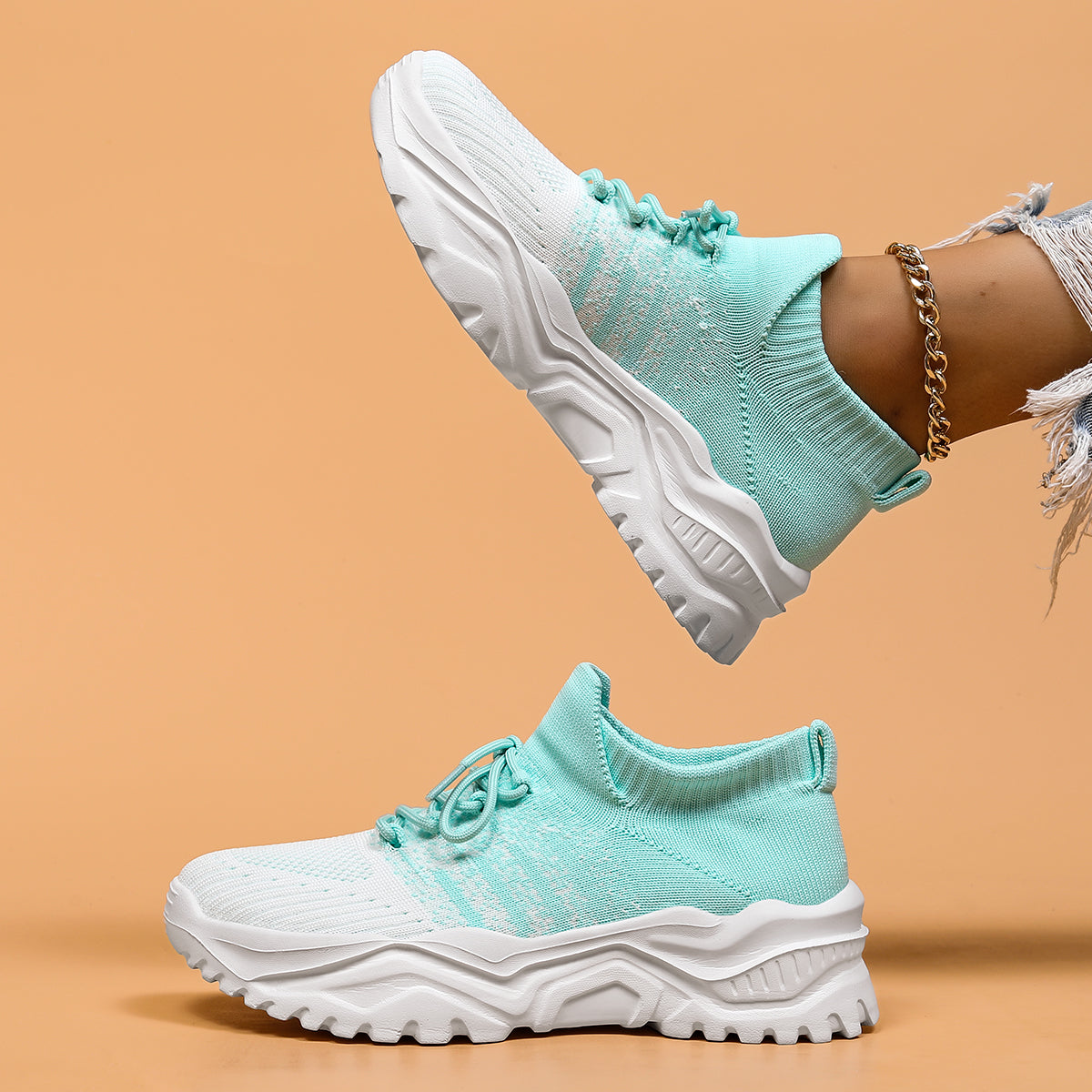 Side view of mint green and white gradient knit sneakers with thick white soles, one shoe held above the other. 11