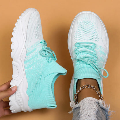 Top-down view of mint green and white gradient knit sneakers with chunky white soles, one held up and one worn. 12
